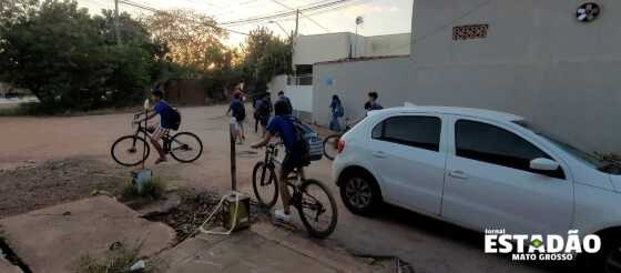 Alunos dividindo rua com carros e buracos no Parque Cuiabá.